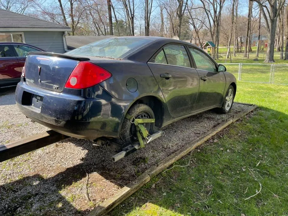 Older Pontiac G6 sedan parked in an Indianapolis driveway, the kind of vehicle Indiana junk car title laws apply to