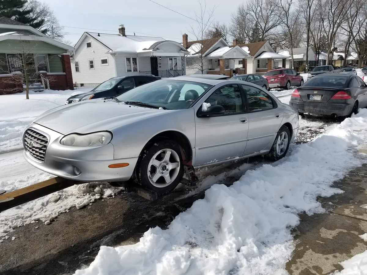 A snowed-in sedan propped on wooden ramps, the kind of stuck vehicle our drivers winch out at no extra charge