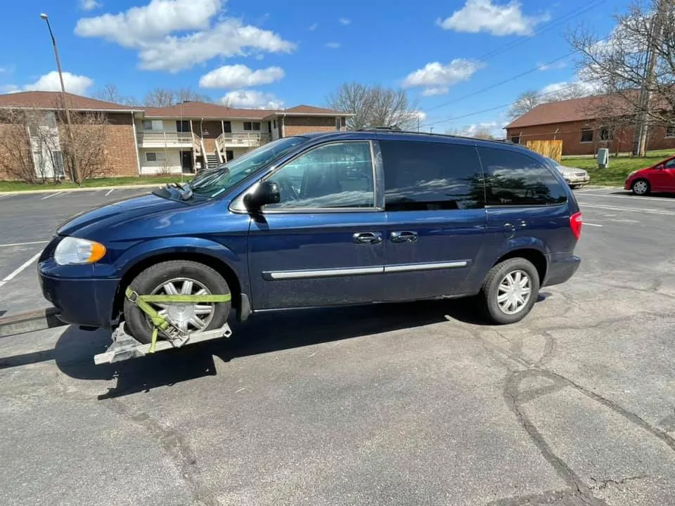 Blue minivan secured to a tow dolly on an Indianapolis street after its owner handed over the signed title and photo ID
