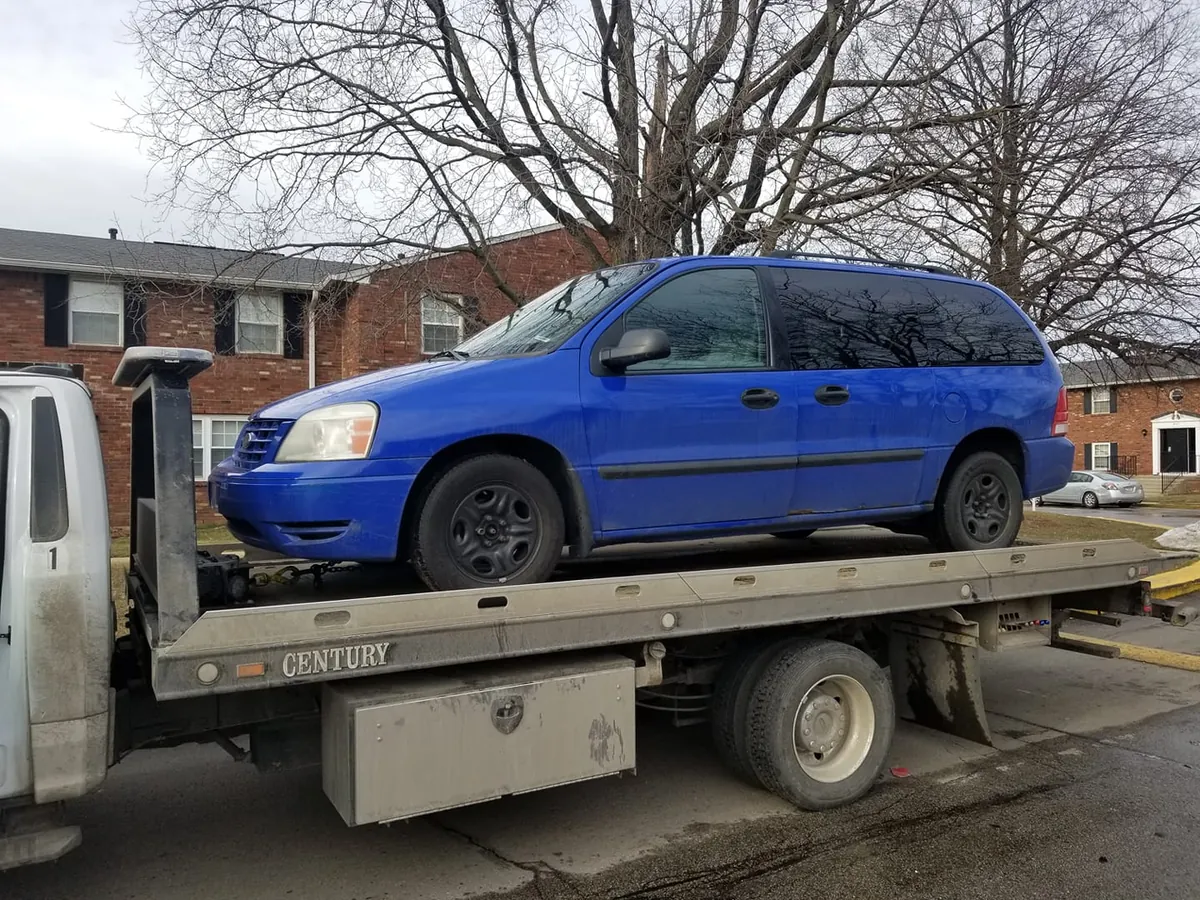 A wrecked minivan secured on a flatbed tow truck -- free towing is included with every wrecked car pickup in Indianapolis